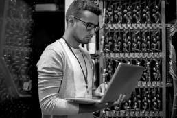 A man holding a laptop in a server room