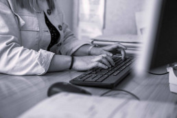 women on computer at desk typing an email on black keyboard